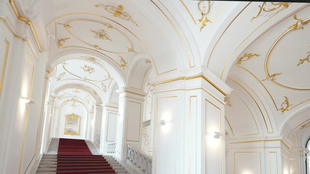Internal staircase in palace, white walls and ceiling vaults are decorated with gold-colored monograms in Bratislava castle. Deserted staircases lead to upper floors and living spaces