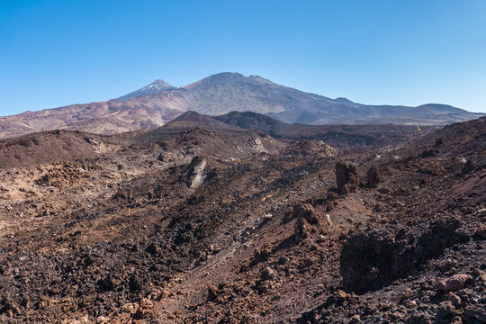 Winter view on colorful volcano Pico del Teide with snow spots from hiking trail Samara. Mountains and lava fields against blue sky. El Teide National Park, Tenerife, Canary Islands, Spain