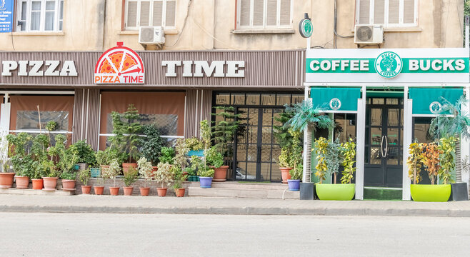 Algiers, Algeria - November 8, 2024: Pizza Time and a coffee shop facade on the main street of Val D'Hydra features a logo named "Coffee Bucks" with a striking resemblance to the Starbucks emblem.