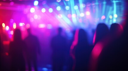 Fototapeta premium Blurry silhouettes of people dancing at a vibrant nightclub with colorful lights.