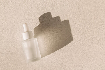 A mock-up of a bottle of moisturizing serum with a pipette on a textured white background. Frosted glass flask with an anti-aging essence dropper.
