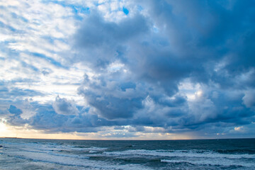 Dark sky over the sea. Low clouds over the water in the bay. Background with a tense panorama of nature before a storm at sunset.