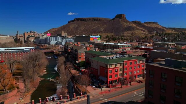 Historic downtown Golden Colorado aerial drone Clear Creek River North Table Mountain Coors Beer Factory Golden Gate Canyon winter snow sunny morning afternoon blue sky businesses buildings pan left