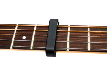 Black guitar capo clamped on wooden fretboard isolated with transparent background
