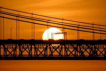 Sunset sky and 25 de Abril bridge in Lisbon with cars and cables in