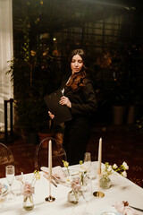 A young White female wedding planner is standing beside a candlelit table with elegant white...