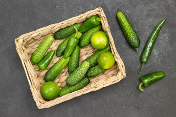 Cucumbers, peppers and limes in rattan basket.