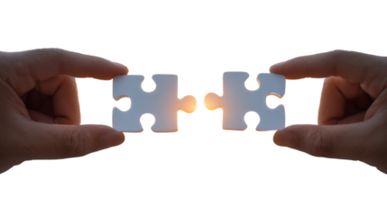 Two hands holding a puzzle piece with a light shining on it