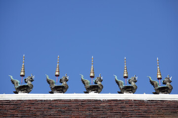 Ornate Temple Roof with Mythical Creatures Against Clear Blue Sky