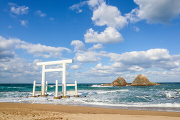 A serene coastal view featuring the iconic white torii gate in the sea, japan.