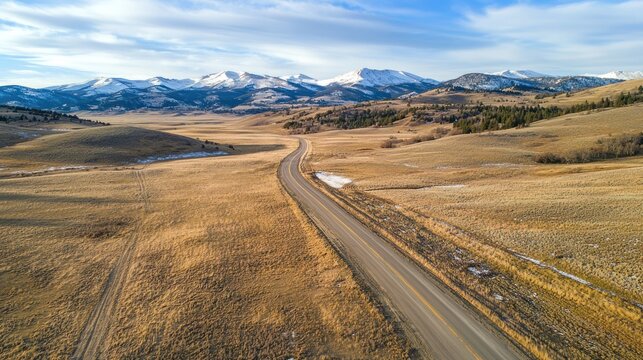 A drone shot capturing an endless stretch of rolling hills leading into snow-capped mountains