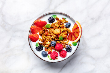 Granola with yogurt and fresh fruit. Organic gourmet muesli with ingredients, overhead flat lay shot on a marble table