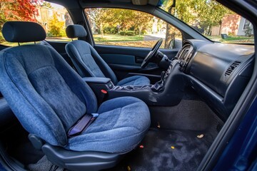 Cozy Interior of a Car with Blue Upholstery and Autumn Leaves on the Ground, Showcasing Comfort and Style in an Inviting Atmosphere