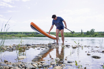 Young man carrying sup board after water surf session