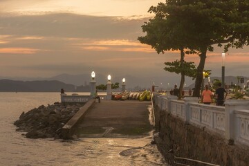 Santos city, Brazil. Sunset at Ponta da Praia. Coastal sidewalk, wall and boat access ramp. People enjoying the late afternoon.