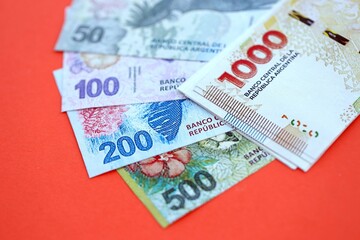 Obraz premium Argentine pesos money bills in big amount lies on red color table close up
