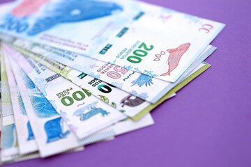Argentine pesos money bills in big amount lies on purple color table close up
