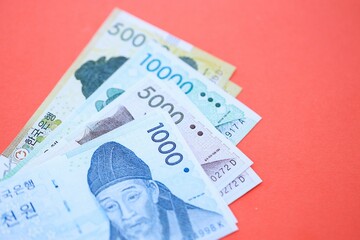 South Korean won money bills in big amount lies on red color table close up