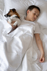 little boy sleeping with dog on white bed