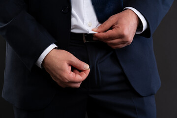 Man adjusting shirt and closing pants zipper.