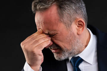 Businessman in pain holding forehead.