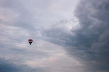 Hot air balloon flying under dramatic cloudy sky