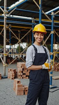 Jeune femme ouvri&egrave;re sur un chantier de construction, pouce lev&eacute; et sourire confiant

