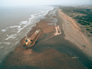 A cargo ship ran aground on the coast after a typhoon. Stranded ship is a huge risk of marine...