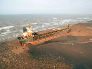 A cargo ship ran aground on the coast after a typhoon. Stranded ship is a huge risk of marine...