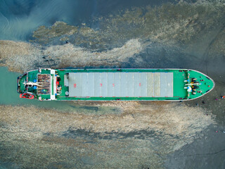 A cargo ship ran aground on the coast after a typhoon. Stranded ship is a huge risk of marine...
