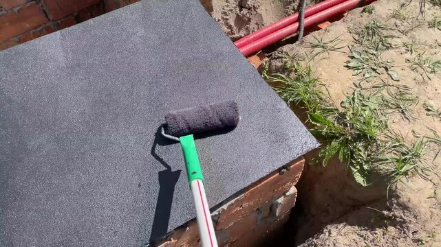 worker applying bitumen mastic for roof waterproof