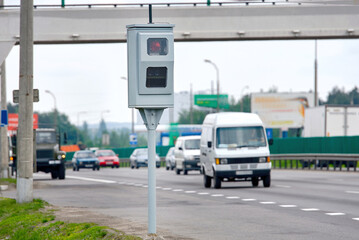 High-tech stationary radar speed camera placed on highway shoulder capturing data of moving vehicles for road law enforcement and traffic monitoring..
