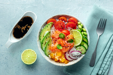 Poke bowl with salmon. Hawaiian salad with rice, fish, tomato, and avocado. Healthy diet. Shot from above with soy sauce