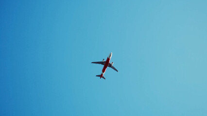 A Plane soaring high in Blue Sky: An aerial view of an airplane gracefully soaring through a clear, expansive blue sky, symbolizing travel, freedom, and the spirit of flight.