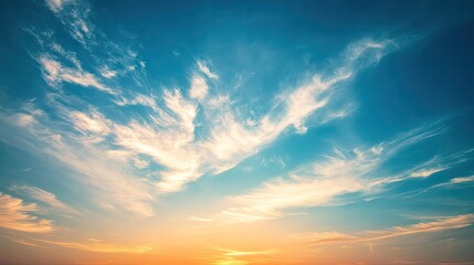 Obraz premium Vibrant sunset sky with wispy clouds, showcasing warm orange and cool blue hues