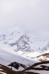 vertical photo of a mountain peak in the snow . A small gazebo stands under high mountains