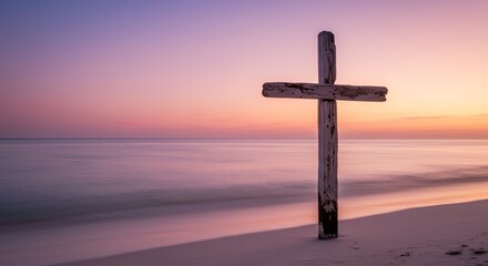 Wooden cross on beach at sunrise