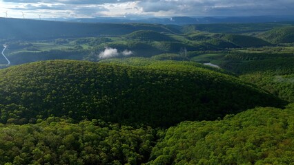 Rolling green hills and mountains under blue sky with clouds in early morning sunlight in West Virginia Mountains