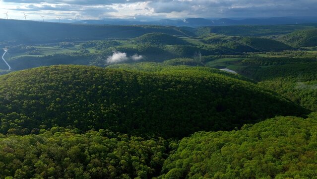 Rolling green hills and mountains under blue sky with clouds in early morning sunlight in West Virginia Mountains