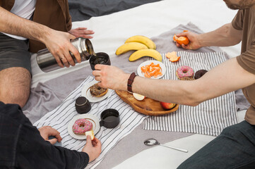 Group of friends and a child enjoying a picnic outdoors. Sharing homemade food, drinks, and playing games on a sunny day. Warm emotions, connection, and authentic lifestyle