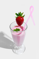 Tall glass of pink strawberry smoothie topped with fresh whole strawberry, green mint leaf and...