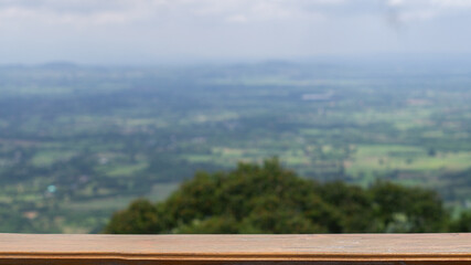 Brown wooden table empty for product presentation related to nature, with blurred background of trees and flat area below, seen from a high angle.