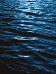 Dark blue water surface with small waves reflecting light abstract nature background close up shot