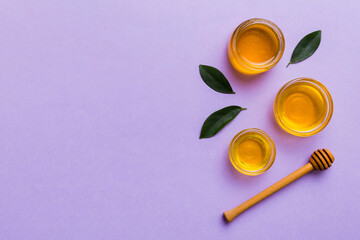 Honey jar with wooden honey dipper on white background top view with copy space. Delicious honey bottle