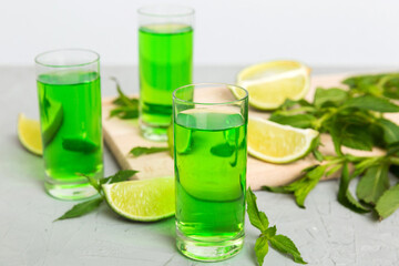 Sweet refreshing mint liqueur, with ice and mint leaves on table background, Shots with lime slice and mint flat lay