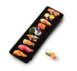 Elegant sushi assortment on a black tray with garnishes, served with wasabi and pickled ginger on the side. High-end Japanese cuisine presentation.