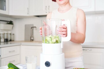 A woman makes a vibrant healthy smoothie with fresh fruits and greens, promoting a healthy...