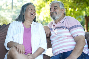 Fototapeta premium Indian Happy Senior Couple having fun and spending quality leisure time in vacation time after retirement at park. Concept of senior citizen living