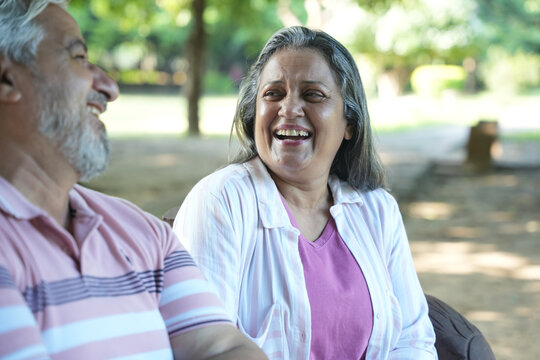 Indian or asian happy smiling senior couple outdoors. Active senior couple having fun talking holding hands and bonding while walking on a date in park together. Bonding, love and relation