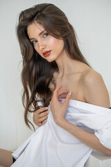 Portrait of a young beautiful brunette model in a white shirt